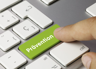 Das Bild zeigt einen Finger, der auf eine Taste einer Tastatur drückt. Auf der Taste steht das Wort "Prävention".